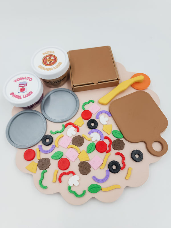 Tiny Pizza Chef playdough kit with tomato-scented dough jars, pizza box, round pizza base moulds, chopping board, and colourful topping pieces including olives, capsicum, and mushrooms