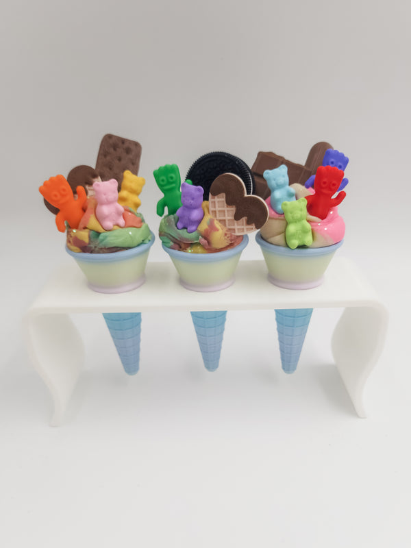Three small ice cream cones with colorful candy pieces on a white background